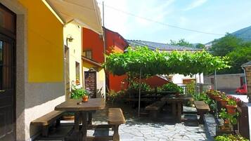 An outdoor patio with stone flooring, wooden tables, and benches.