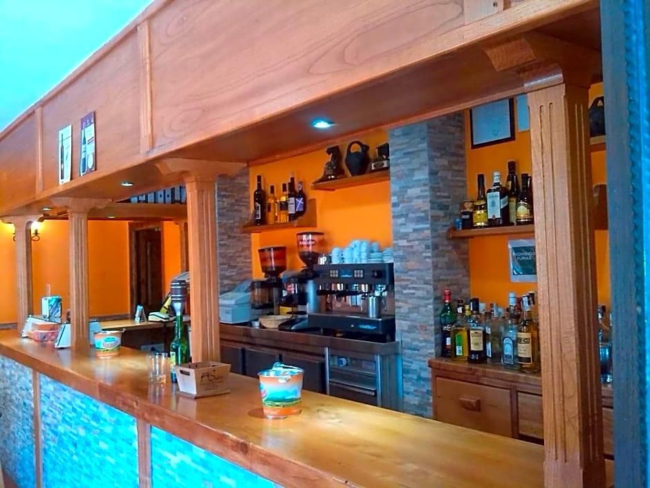 A bar area with a wooden counter, shelves with bottles, and a coffee machine.