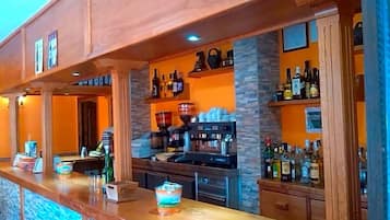 A bar area with a wooden counter, shelves with bottles, and a coffee machine.