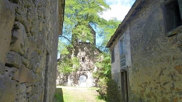 Ein schmaler Gang mit Steinwänden, ein Gebäude auf der rechten Seite und eine Kirche mit einem Glockenturm in der Ferne.
