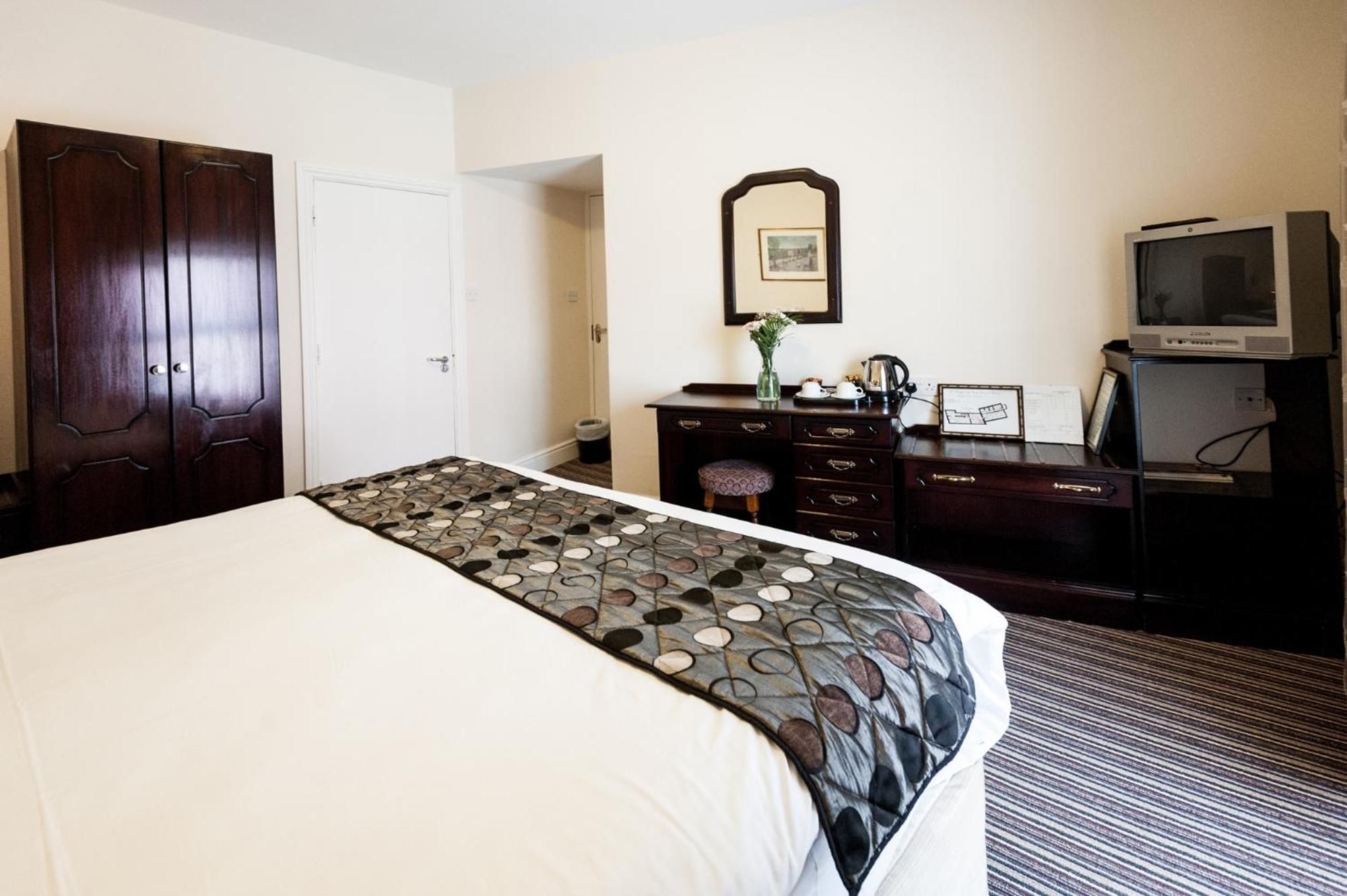 Una habitación de hotel con una cama, un aparador, un televisor y un espejo.