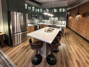 Une cuisine moderne équipée d’un réfrigérateur en acier inoxydable, d’un four à micro-ondes et d’un grand îlot central avec des tabourets de bar.