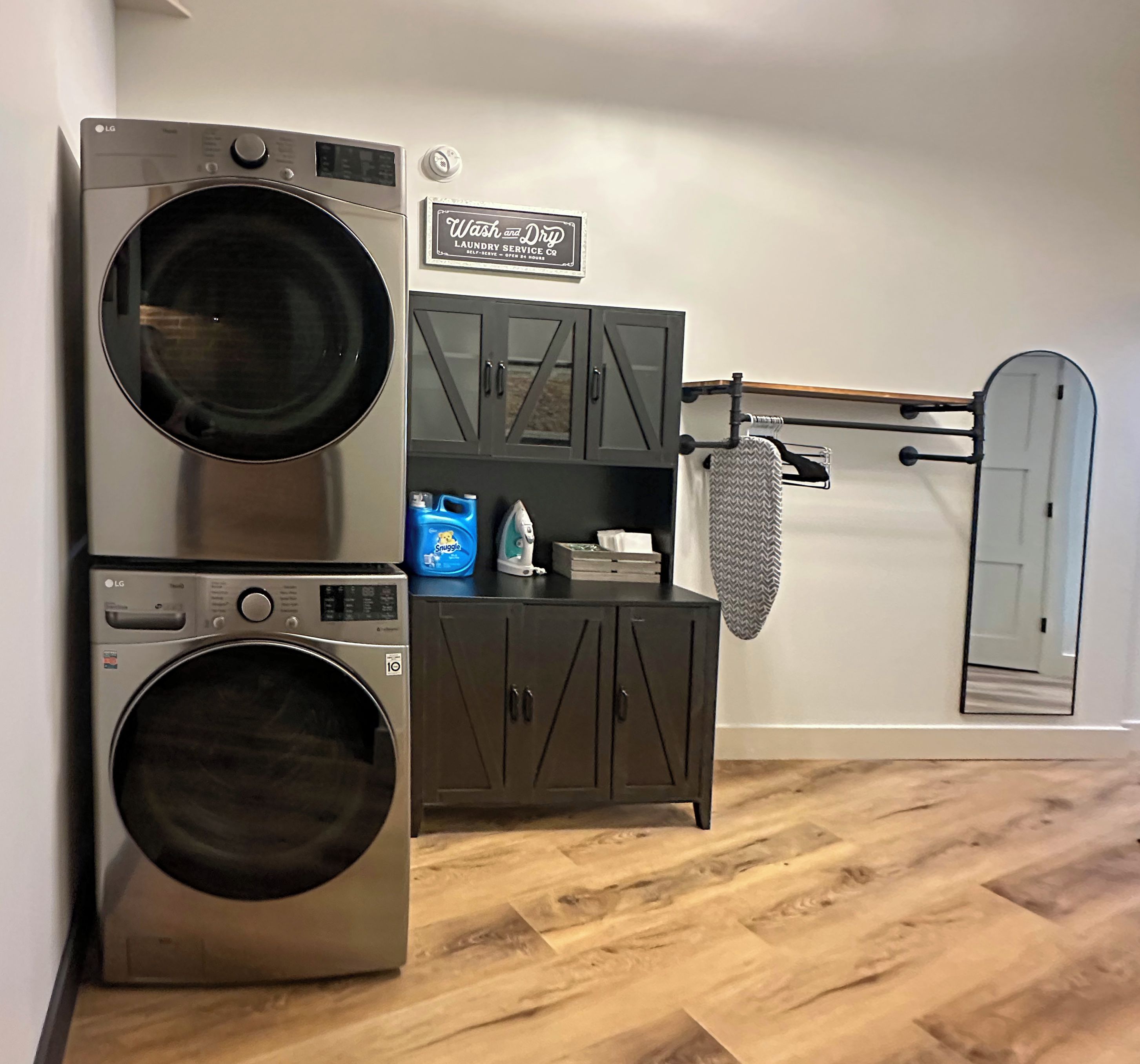 A laundry area with two stacked LG washing machines, a cabinet with storage, and a sign for a laundry service.