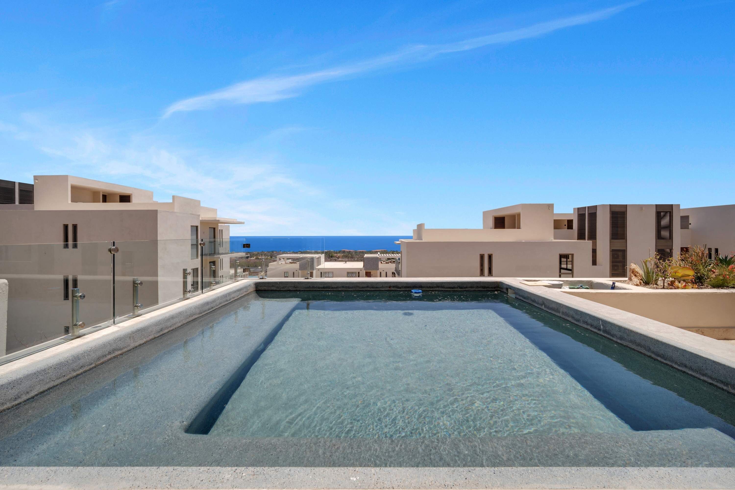 Una piscina en la azotea con agua cristalina y azul, rodeada de edificios modernos con balcones.