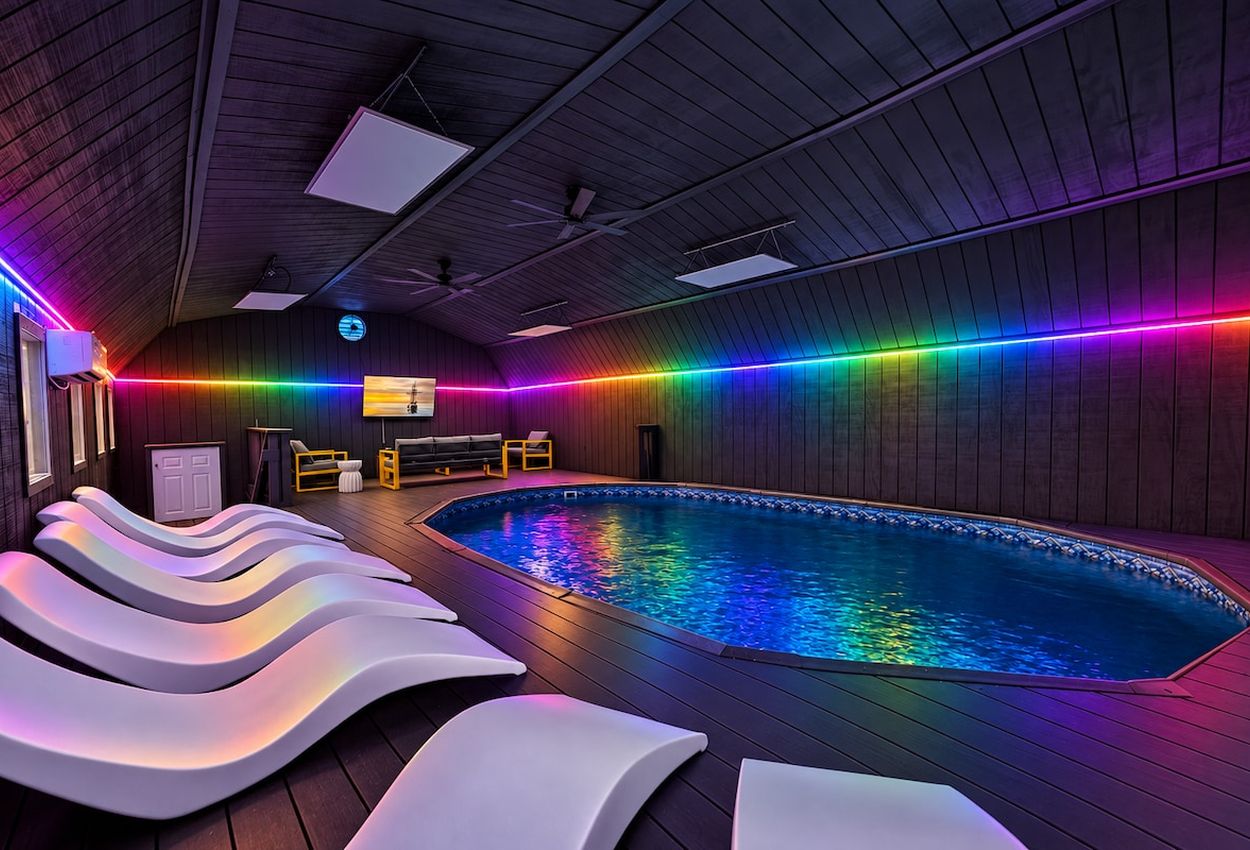 A swimming pool with a curved edge, surrounded by lounge chairs and a wooden deck.