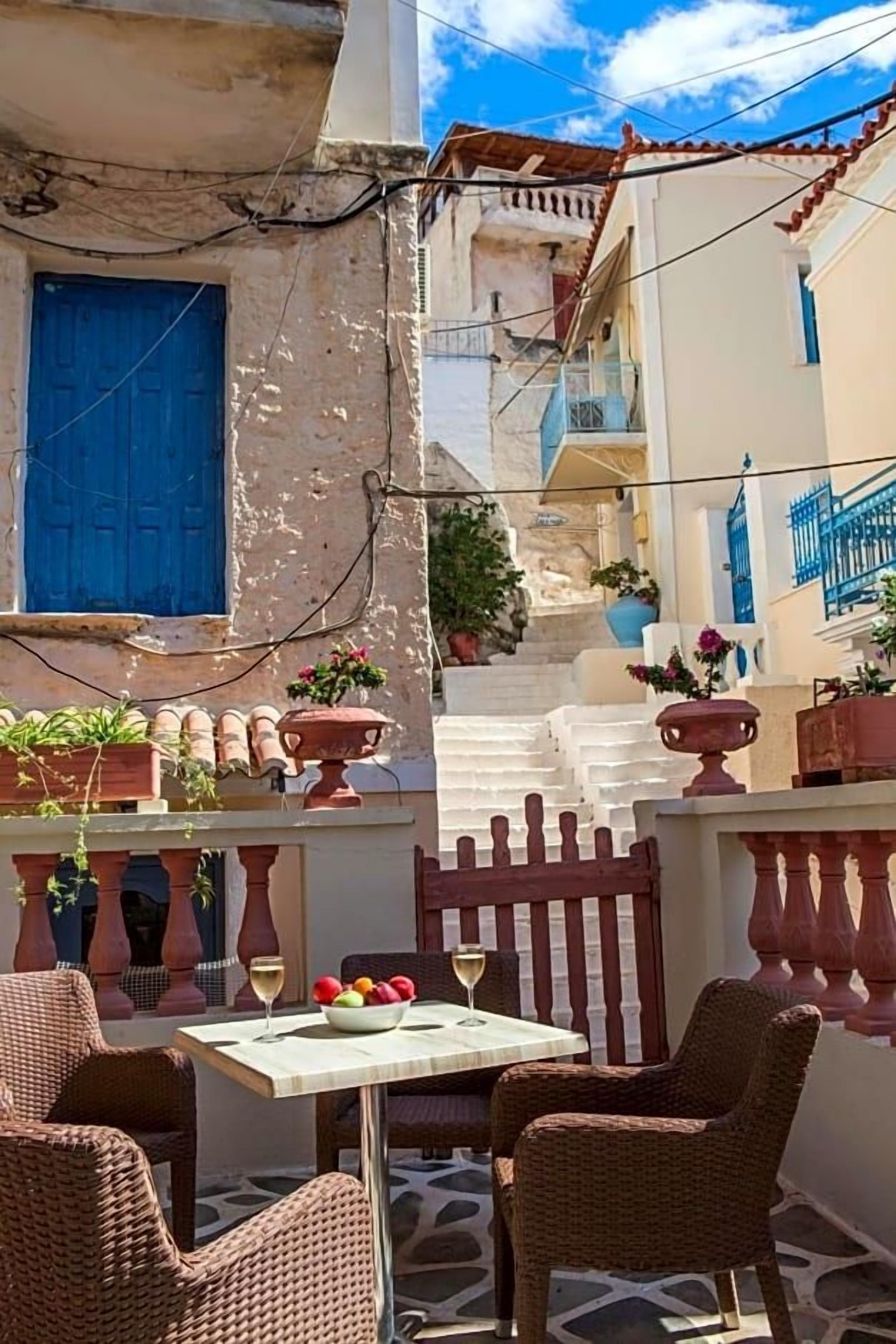 Una terraza con mobiliario de mimbre, una mesa y plantas en macetas.