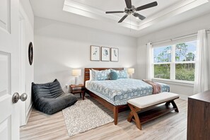 A bedroom with a bed, bedside tables, a bench, a ceiling fan, and a window with blinds. - Vermilion Cove: Windmark beach, pool, bikes & more (Port St. Joe)