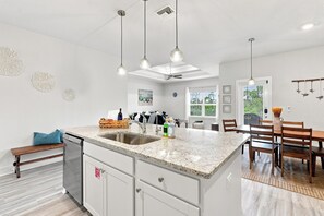 A modern kitchen with a central island, stainless steel sink, and pendant lighting.