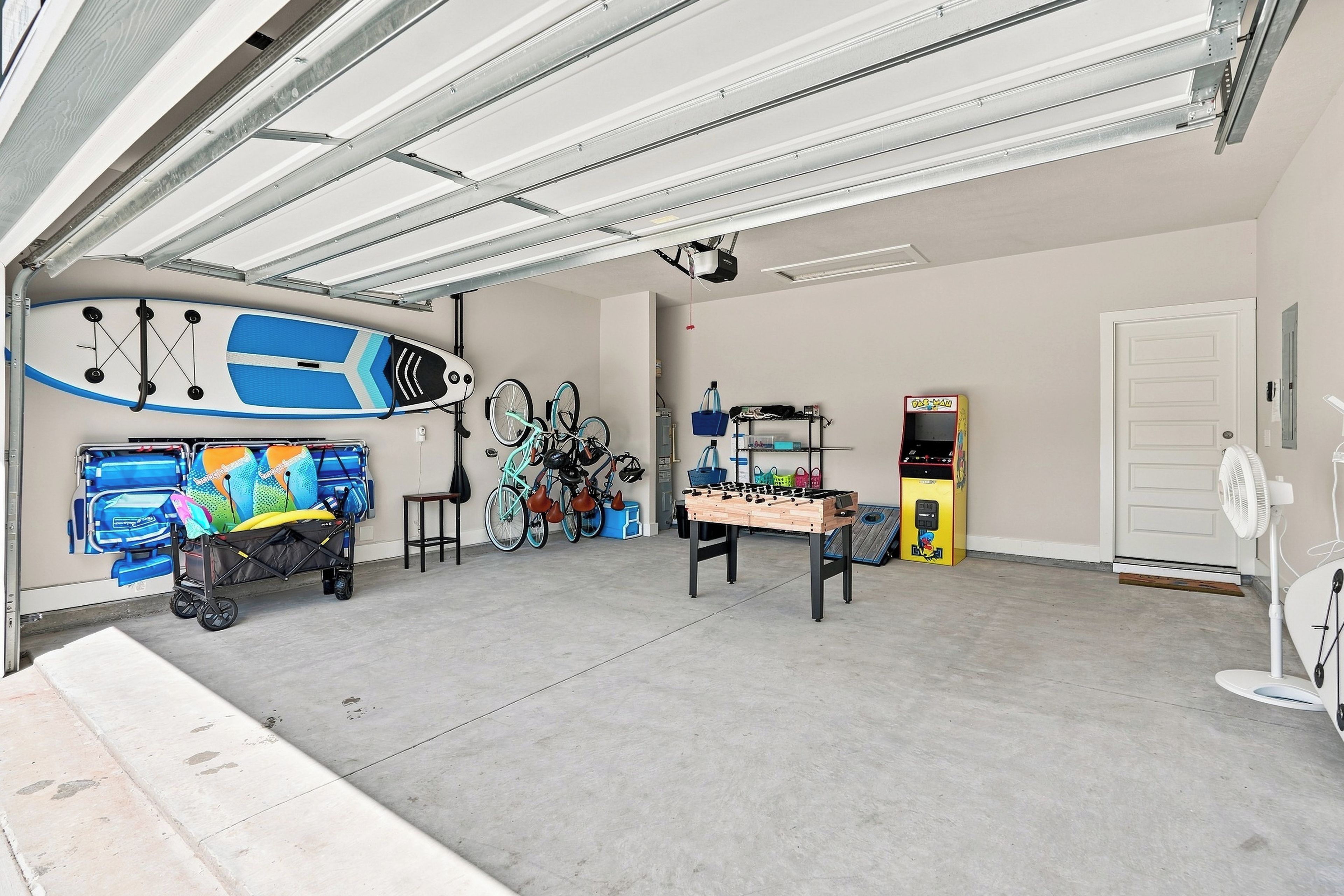 Uma garagem com mesa de pebolim, bicicletas e um carrinho de brinquedo.