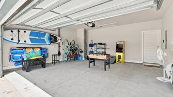 Uma garagem com mesa de pebolim, bicicletas e um carrinho de brinquedo.
