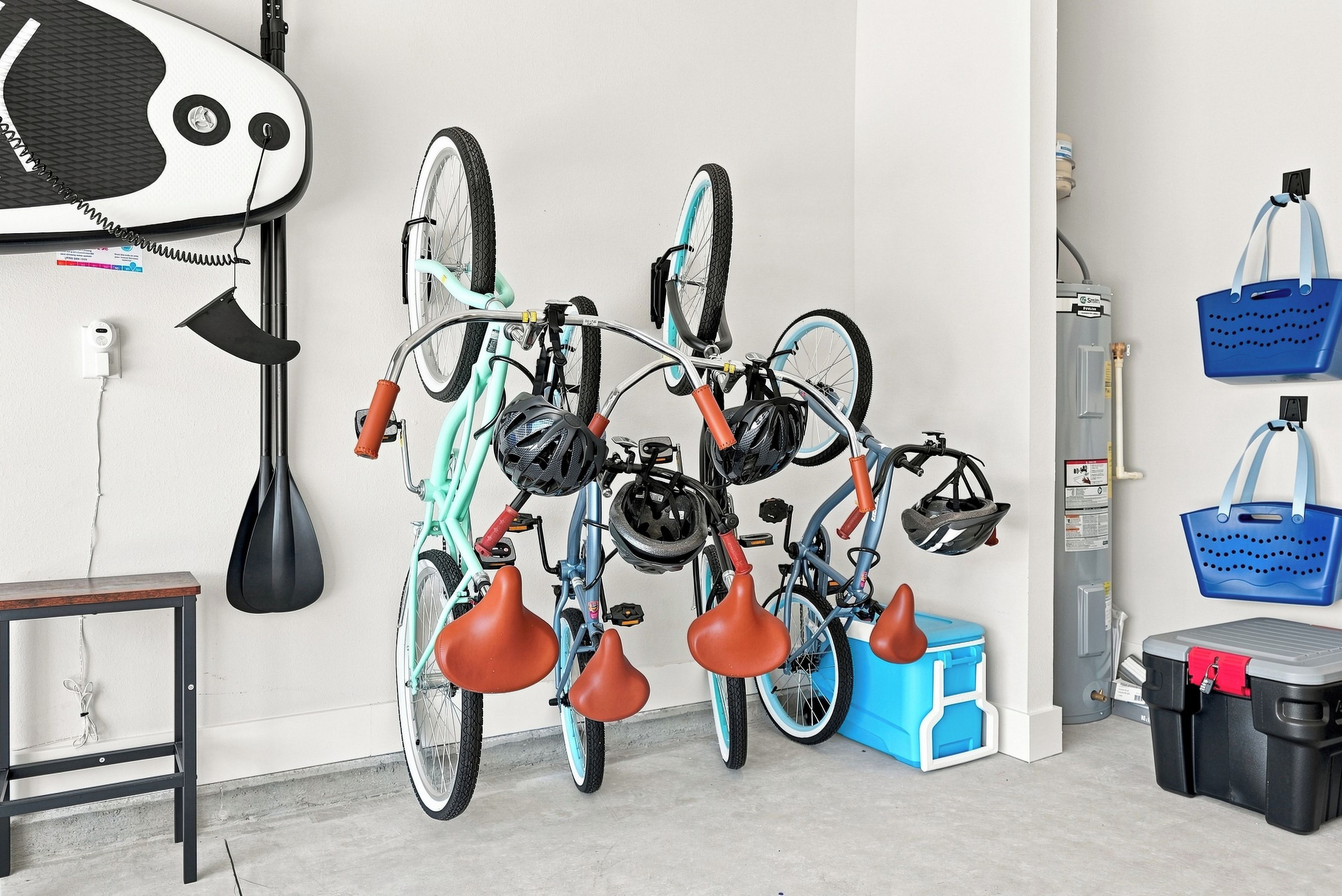 Una stanza con una rastrelliera per biciclette fissata al muro, che contiene due biciclette, una scatola portaoggetti blu e un contenitore nero e rosso.