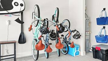 Una stanza con una rastrelliera per biciclette fissata al muro, che contiene due biciclette, una scatola portaoggetti blu e un contenitore nero e rosso.