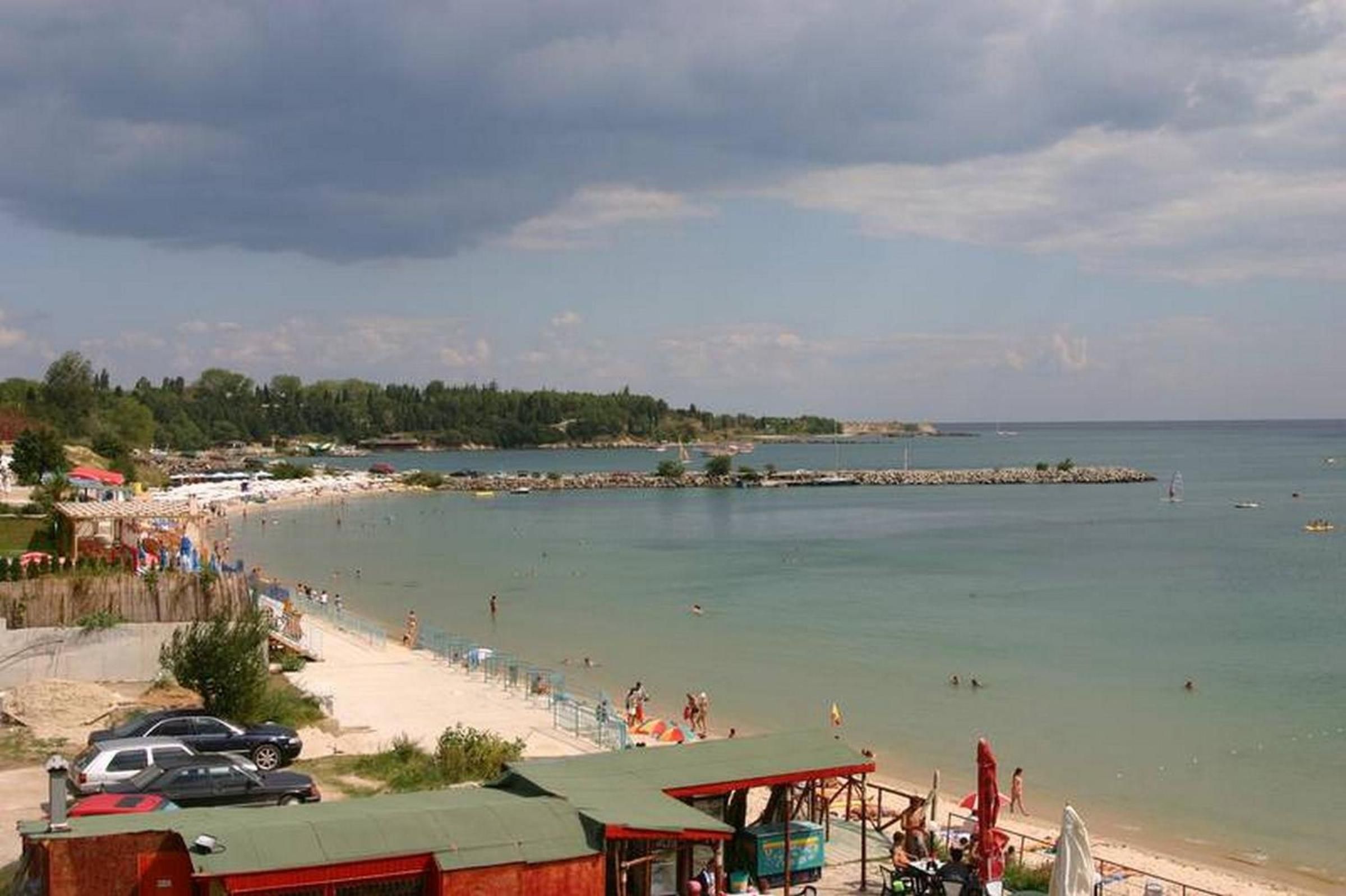 Une scène de plage côtière avec une rive sablonneuse, une jetée et un ciel dégagé.
