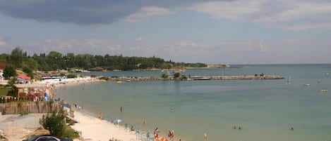 A coastal beach scene with a sandy shore, a pier, and a clear sky.