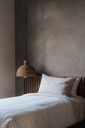 Ein Schlafzimmer mit einem Bett, einer hängenden Gewebedecke und einer schlichten Wand.