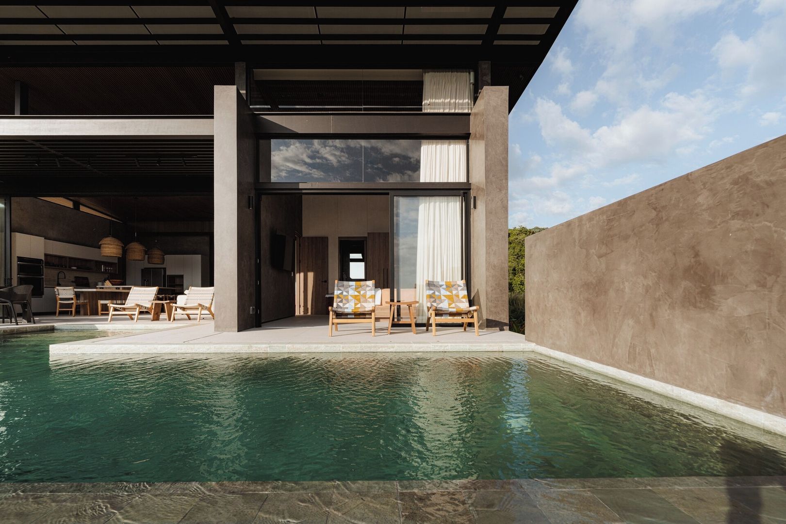 A modern outdoor pool area with lounge chairs and a dining setup.