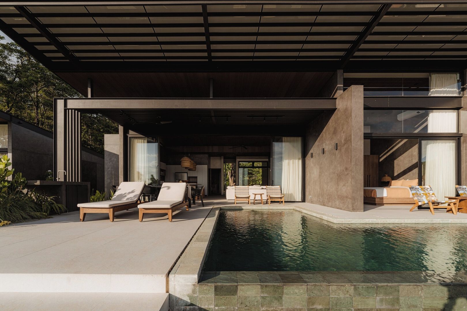 Un espace piscine extérieur moderne, doté de chaises longues et d’un coin salon abrité.