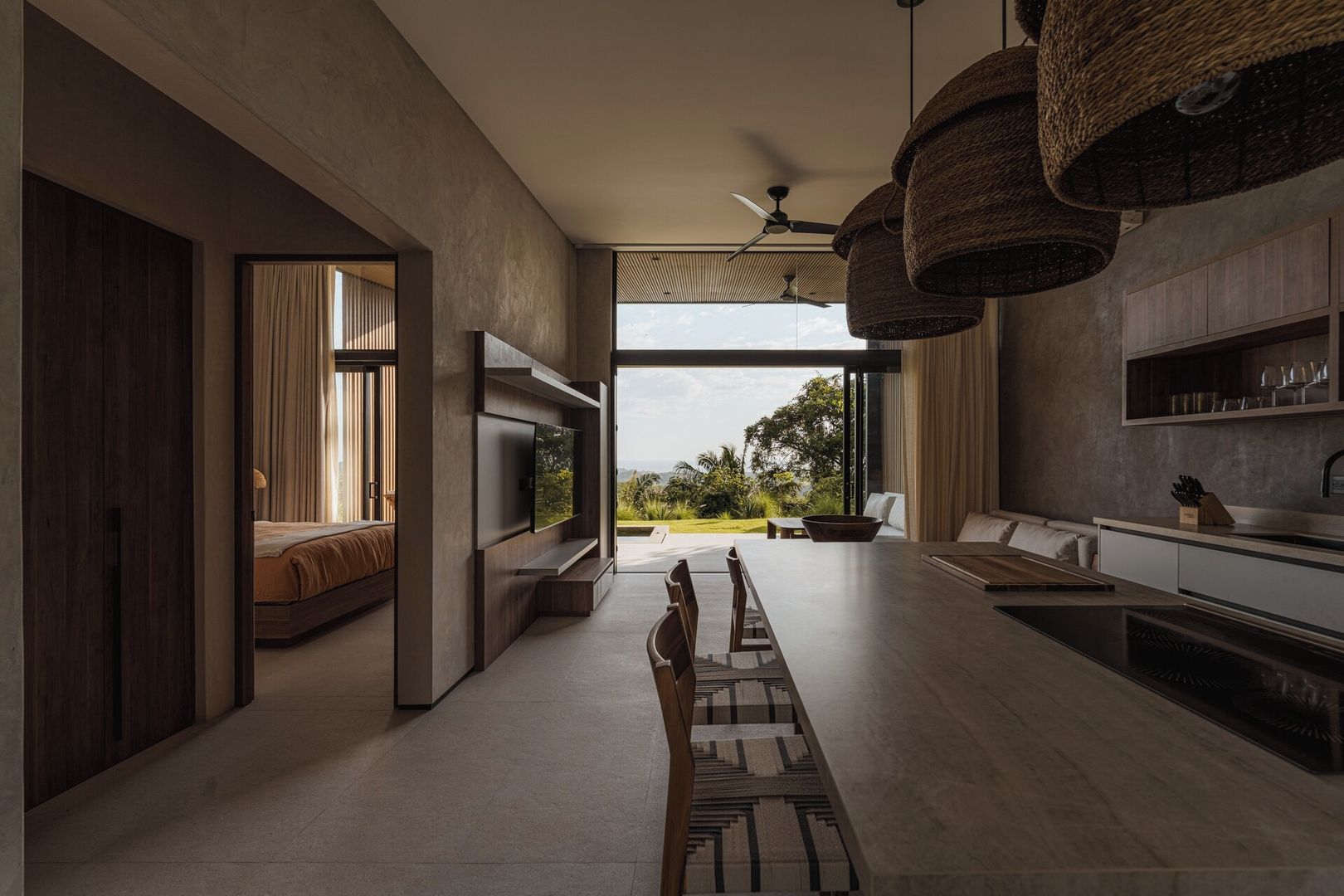 A modern kitchen with a built-in oven, a dining area with a long table, and a view of the outdoors.