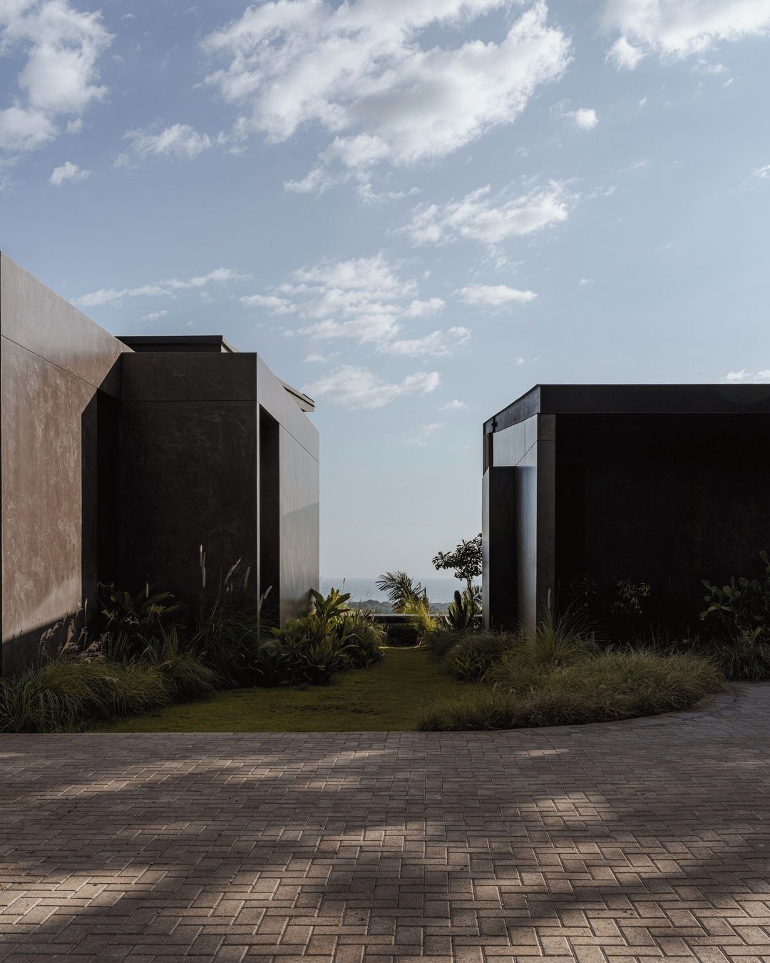 A modern building with a paved walkway and a view of the ocean.