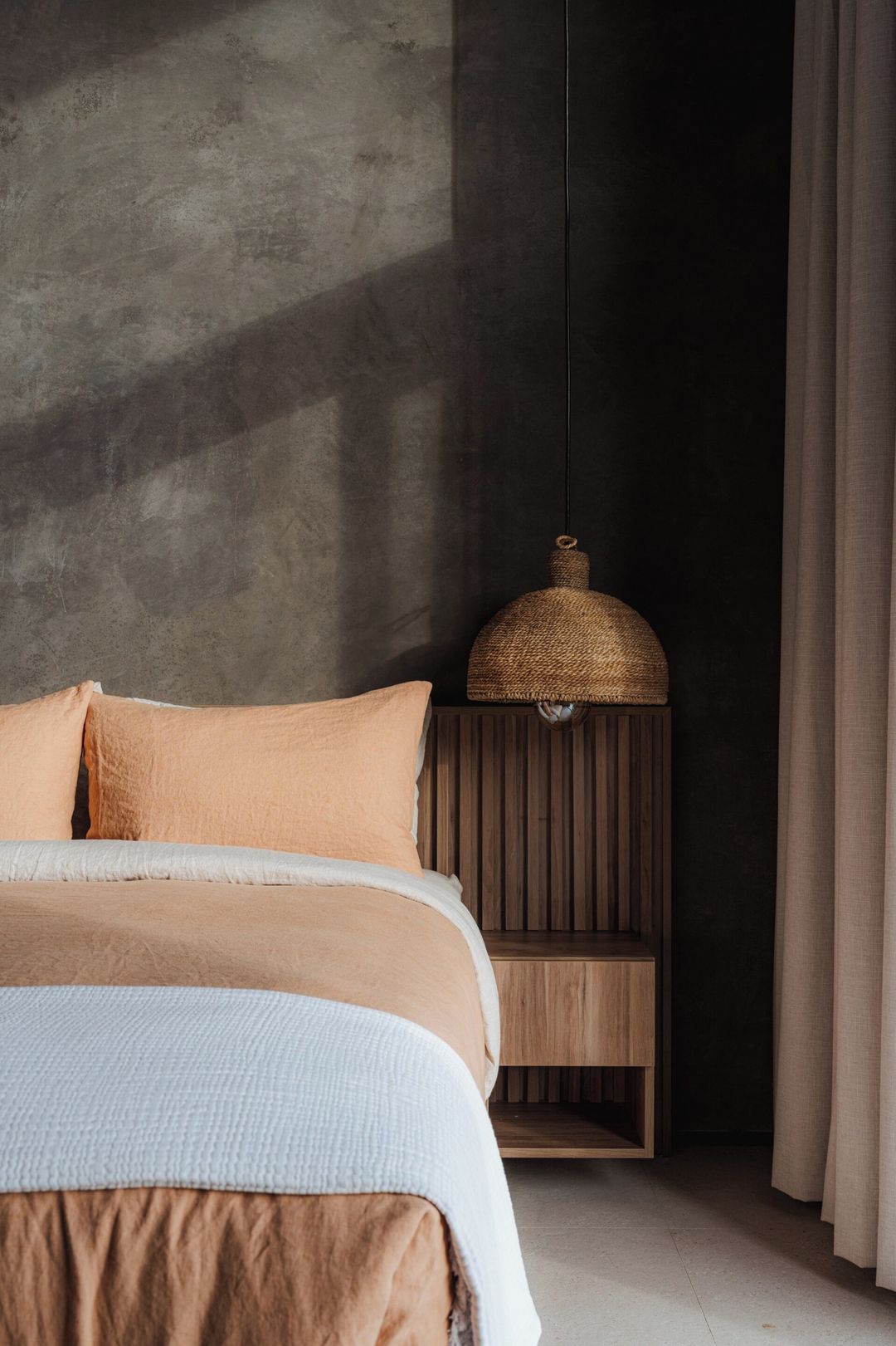 A bedroom with a bed, a nightstand, and a hanging lamp.
