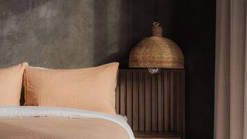 A bedroom with a bed, a nightstand, and a hanging lamp.