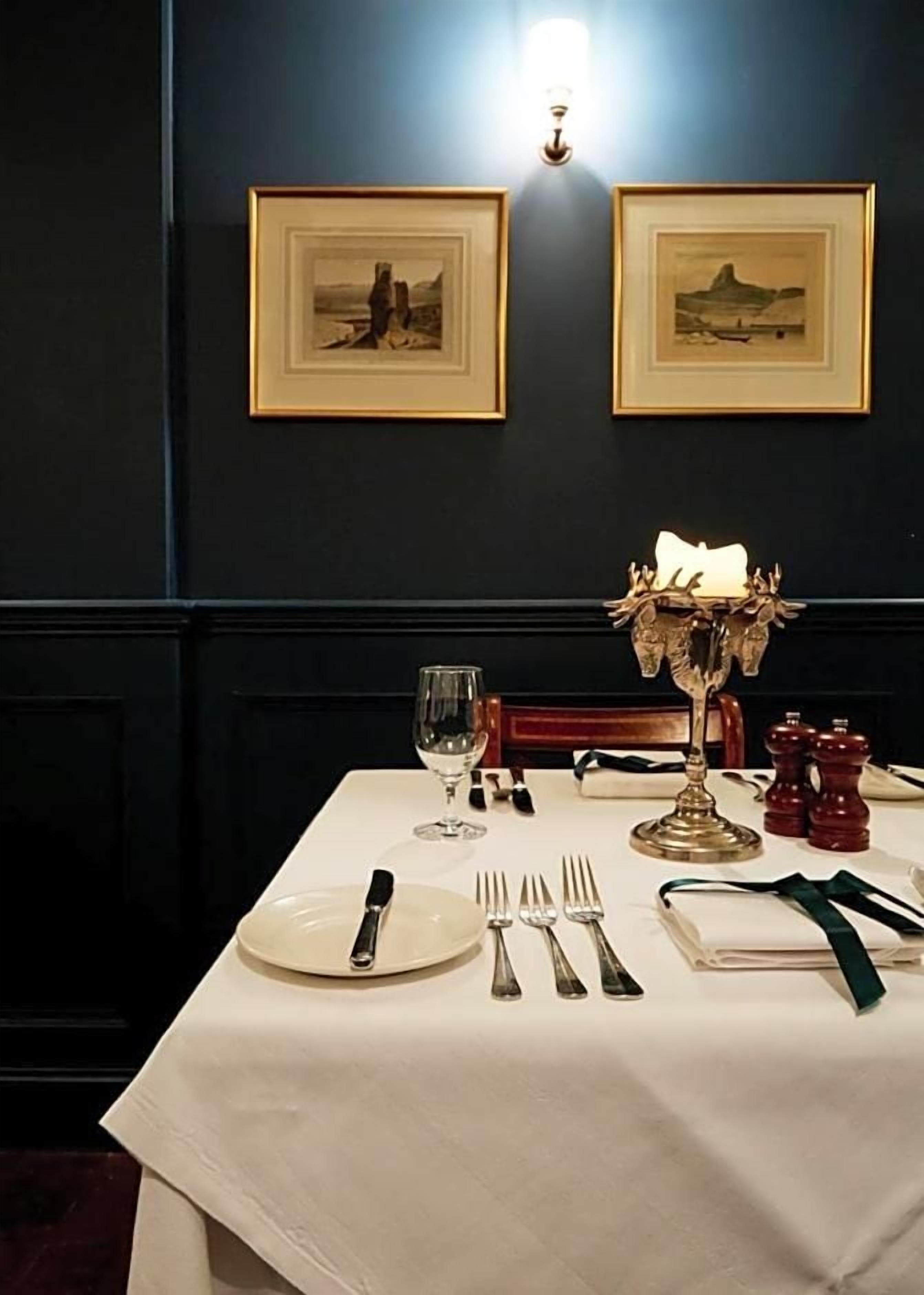 A dining table set with plates, cutlery, a wine glass, and a decorative candelabra.