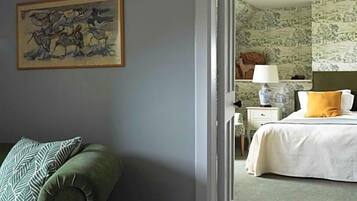 Ein Zimmer mit einem grünen Sessel, einem Bett mit weißem und gelbem Kissen sowie einem Bild an der Wand.