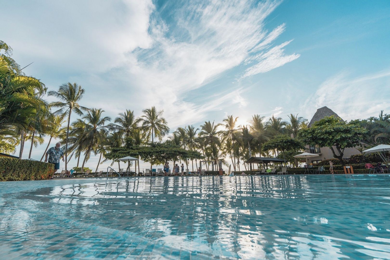 A swimming pool with palm trees and a building in the background.