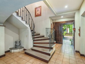 Eine Treppe mit geschwungener Handlauf führt zu einer Tür, einem Blumentopf und einem gerahmten Bild an der Wand.