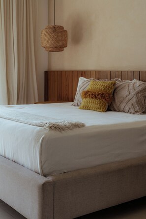 Un lit avec une tête de lit en bois, un luminaire en fibres tressées et un plaid à texture intéressante.