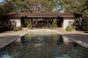 A pool with a pergola structure in the background, surrounded by greenery. - Modern 4BR Villa, All En-Suite · Hacienda Pinilla (Guanacaste)