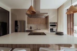 A modern kitchen with a large island, stainless steel appliances, and pendant lighting. - Modern 4BR Villa, All En-Suite · Hacienda Pinilla (Guanacaste)