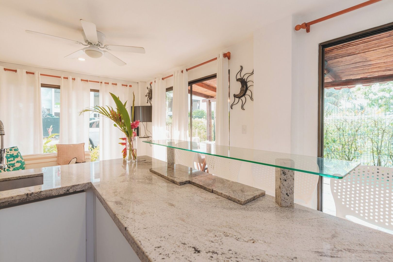 Una cocina moderna con una isla de vidrio, un ventilador de techo y vistas al exterior.