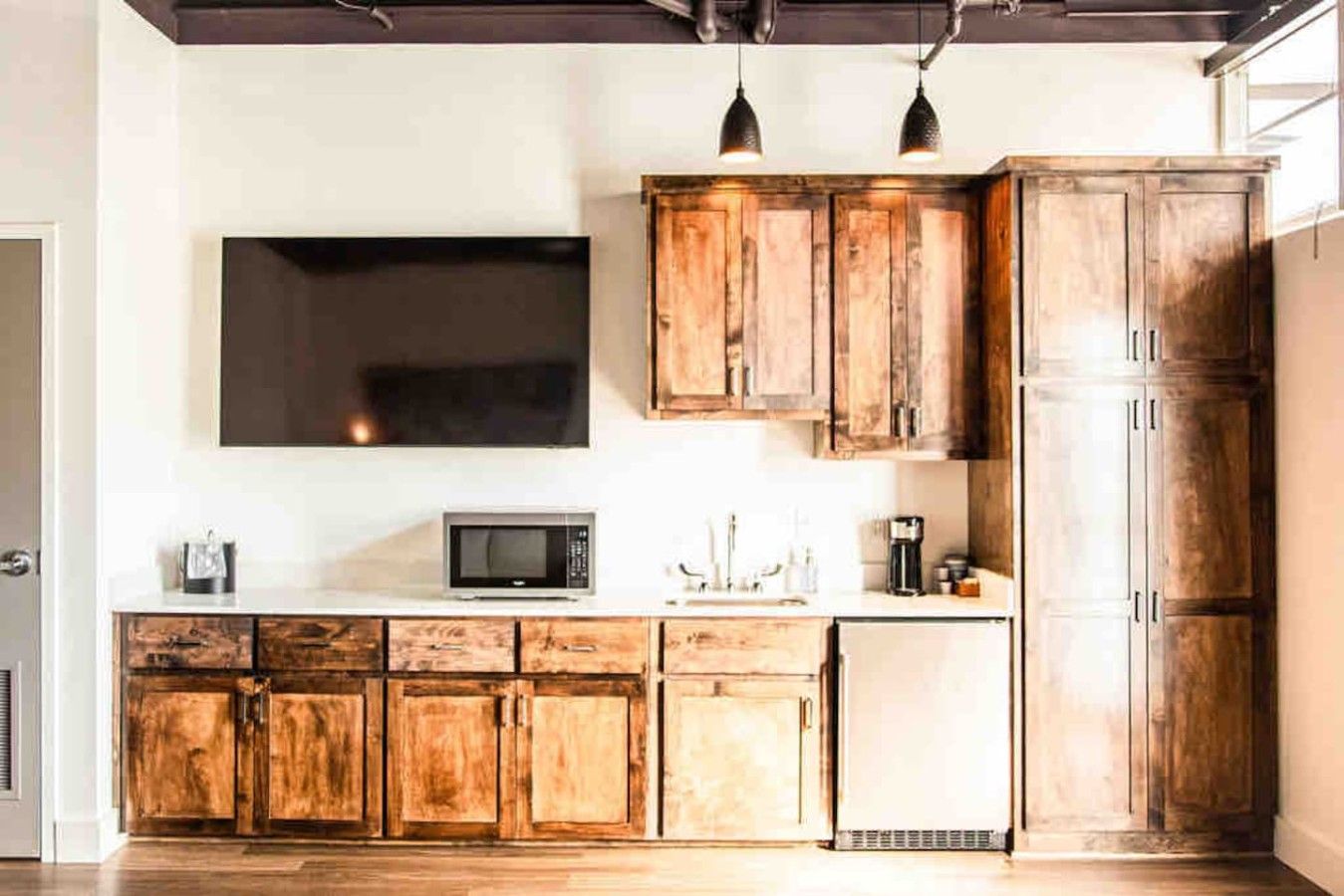 Une cuisine avec des meubles en bois, un four à micro-ondes et des luminaires suspendus.