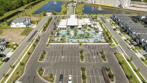 Ein Luftbild eines Hotels mit einem zentral gelegenen Schwimmbad, mehreren Parkplätzen und umliegender Grünfläche.