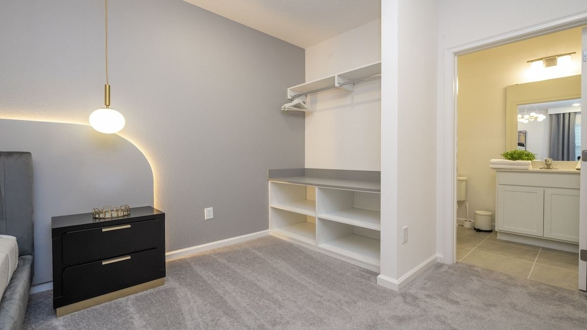 A bedroom with a bed, a bedside table, a wardrobe, and a built-in shelving unit.
