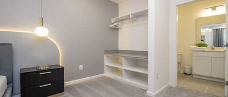 A bedroom with a bed, a bedside table, a wardrobe, and a built-in shelving unit.