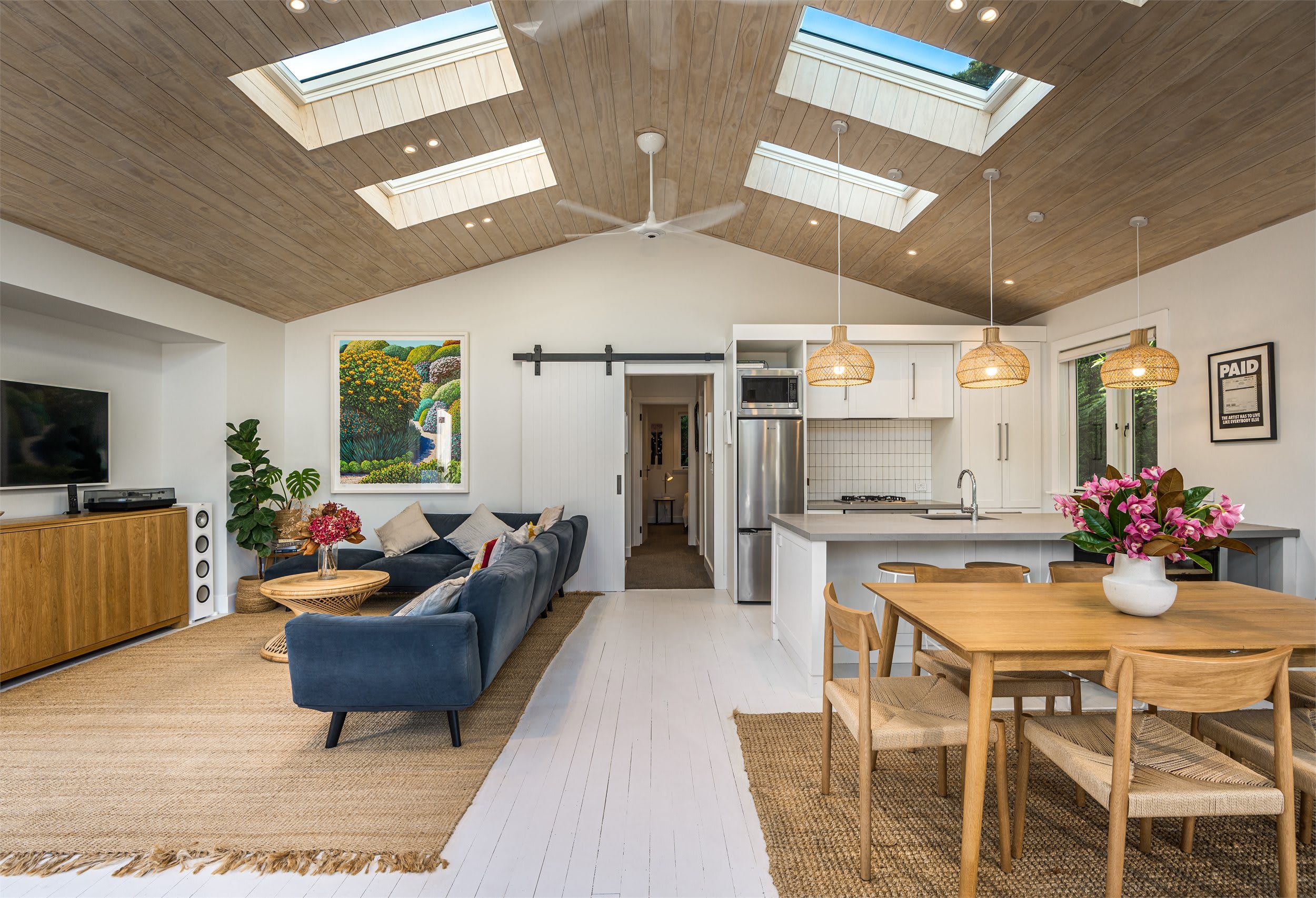 Een modern interieur met een zithoek, keuken en eethoek, met houten plafonds, dakramen en eigentijdse meubels.