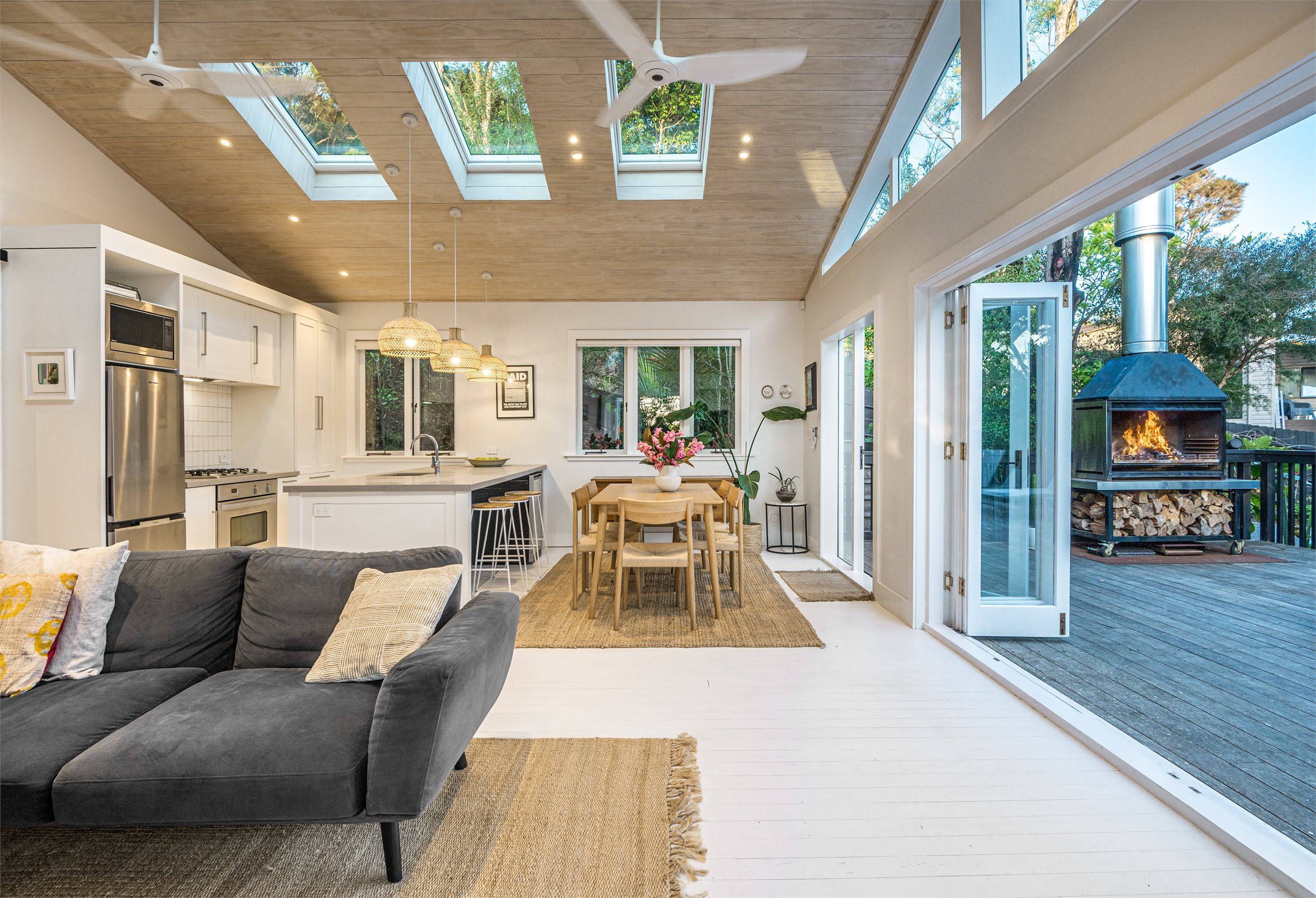 A modern kitchen with a built-in oven, a dining area with a table and chairs, and a large sliding glass door leading to an outdoor deck.
