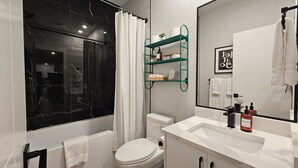 Un baño moderno con bañera, inodoro y tocador con espejo.