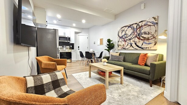Una sala de estar moderna con un sofá, un sillón, una mesa de centro y un televisor de pantalla plana.