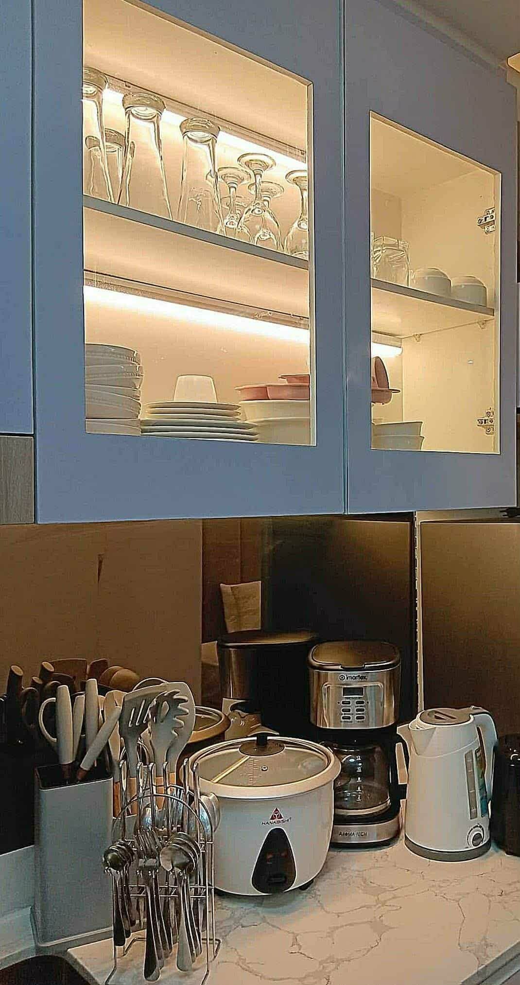 Une cuisine équipée d’un four à micro-ondes encastré, d’une machine à café et d’un porte-épices.