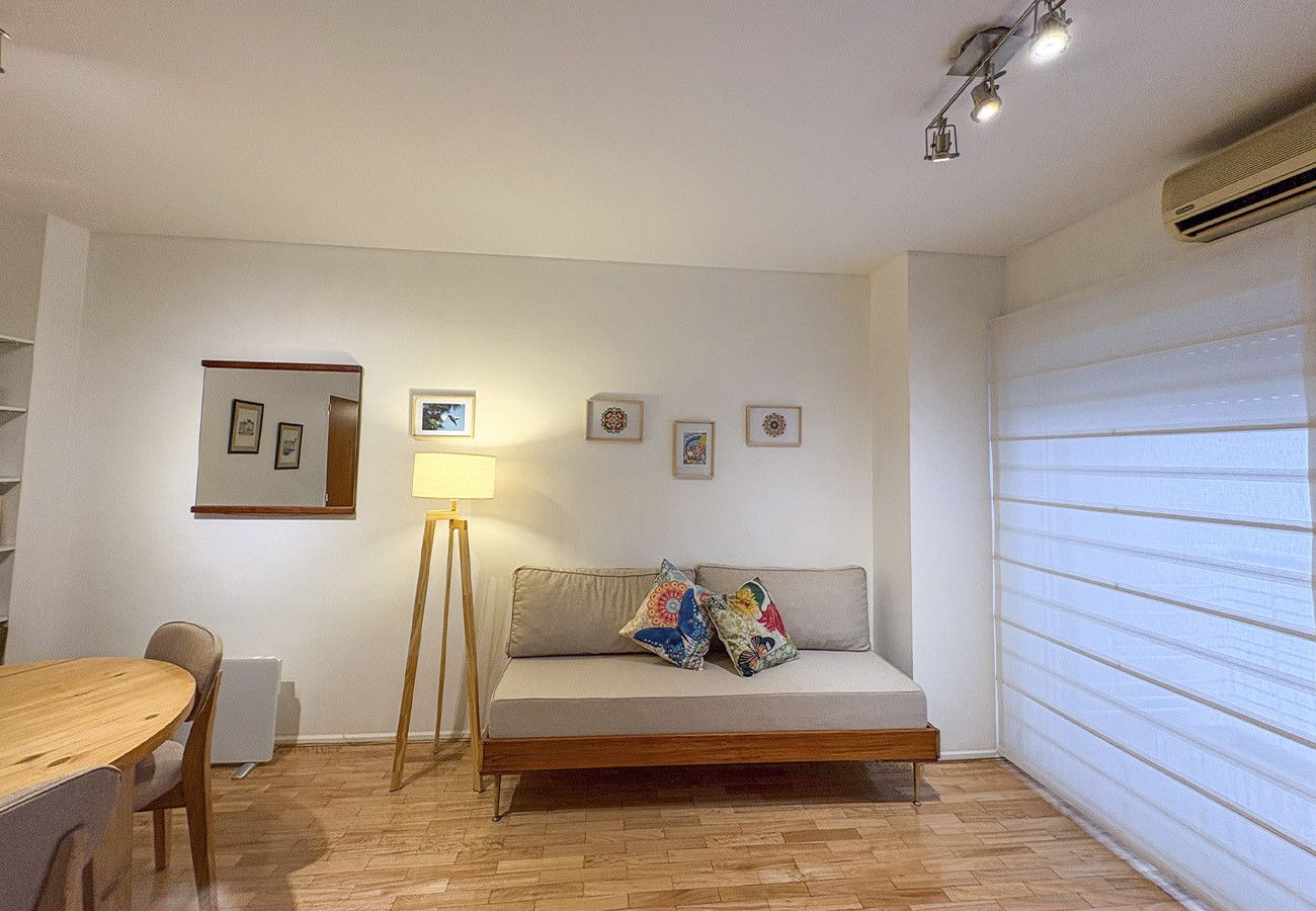 Een kamer met een bank, een eettafel en een lamp. Er hangen prestaties aan de muur.