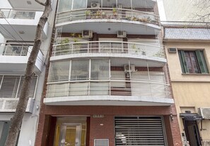 A multi-story building with balconies, air conditioning units, and a storefront with a sign. - One-Bedroom With Balcony in Belgrano | River, Campo Arg de Polo & Chinatown (Buenos Aires)