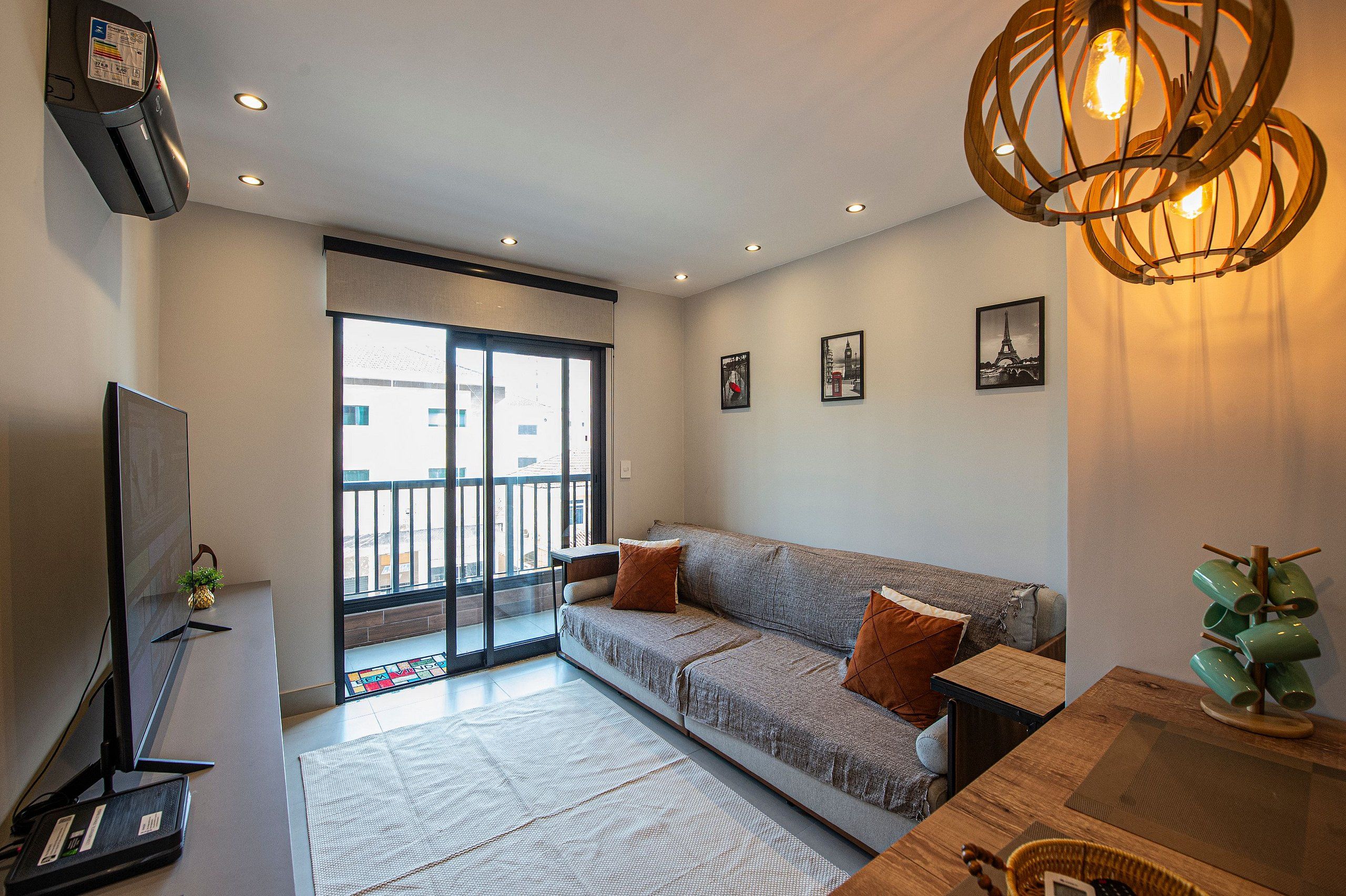 A modern living room with a sofa, a flat-screen TV, and a ceiling light fixture.