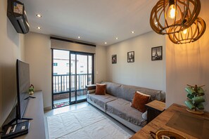 Ein modernes Wohnzimmer mit einer Couch, einem Flachbildfernseher und einer Deckenleuchte.