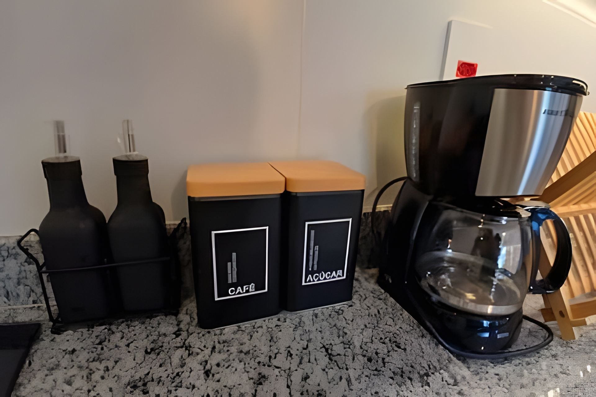 Una cocina con cafetera, dos recipientes negros con etiquetas y una encimera.