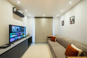 A modern living room with a flat-screen TV, a sofa, and a small table.
