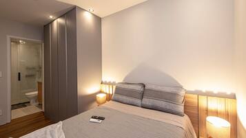 Quarto com cama, abajures, um controle remoto e cabeceira de madeira.