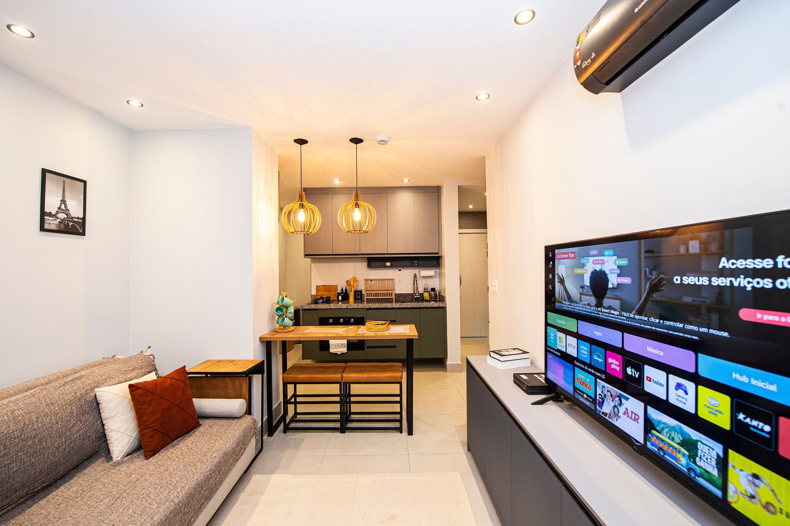 Una sala de estar moderna con un sofá, una mesa de comedor y un televisor que muestra varios canales.